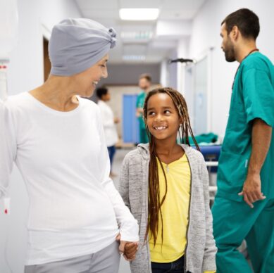 Sick senior woman with cancer hugging her young grandchild in hospital. Family support concept.